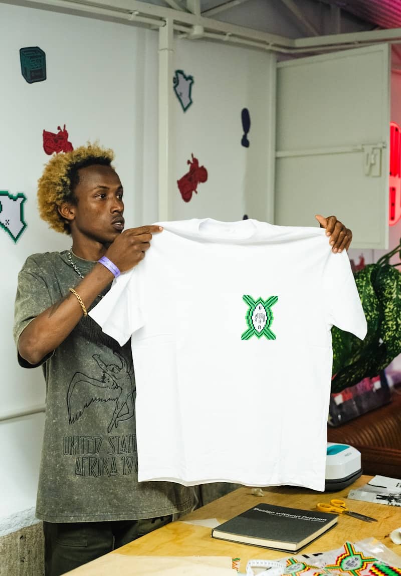 Man holding a white t-shirt with a green emblem.