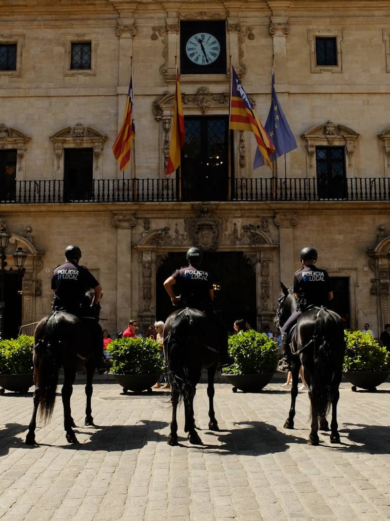Three mounted police officers guard a historic building.