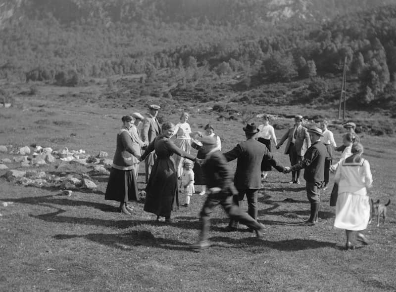 A group of people walking across a grass covered field