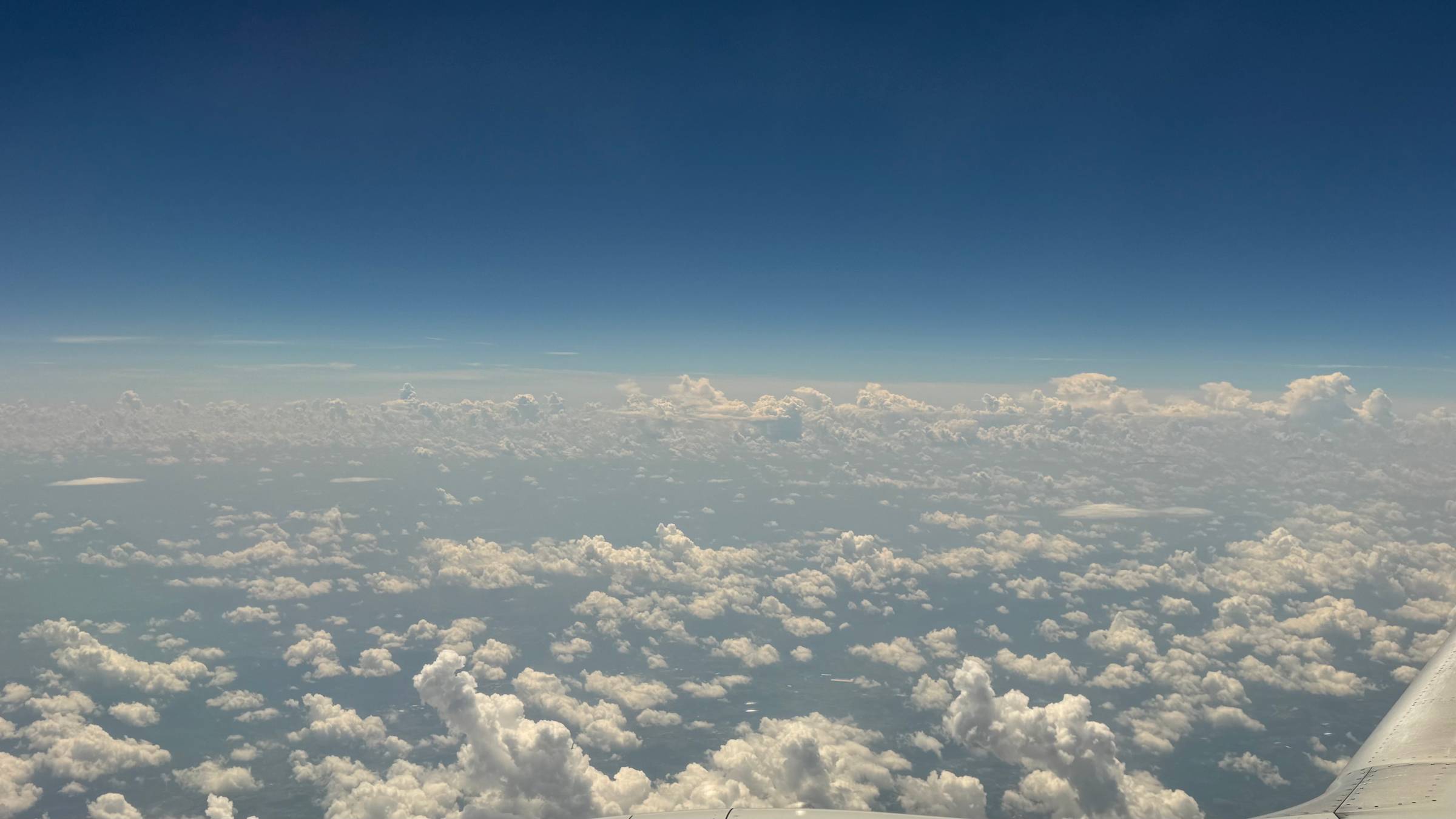 View of blue sky and white fluffy clouds from airplane window.