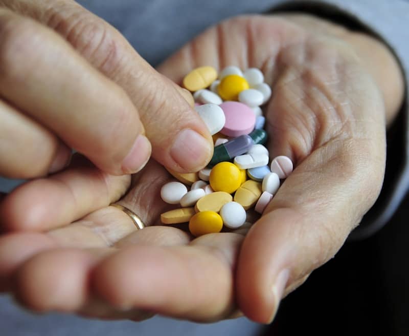 Hands holding a pile of colorful pills