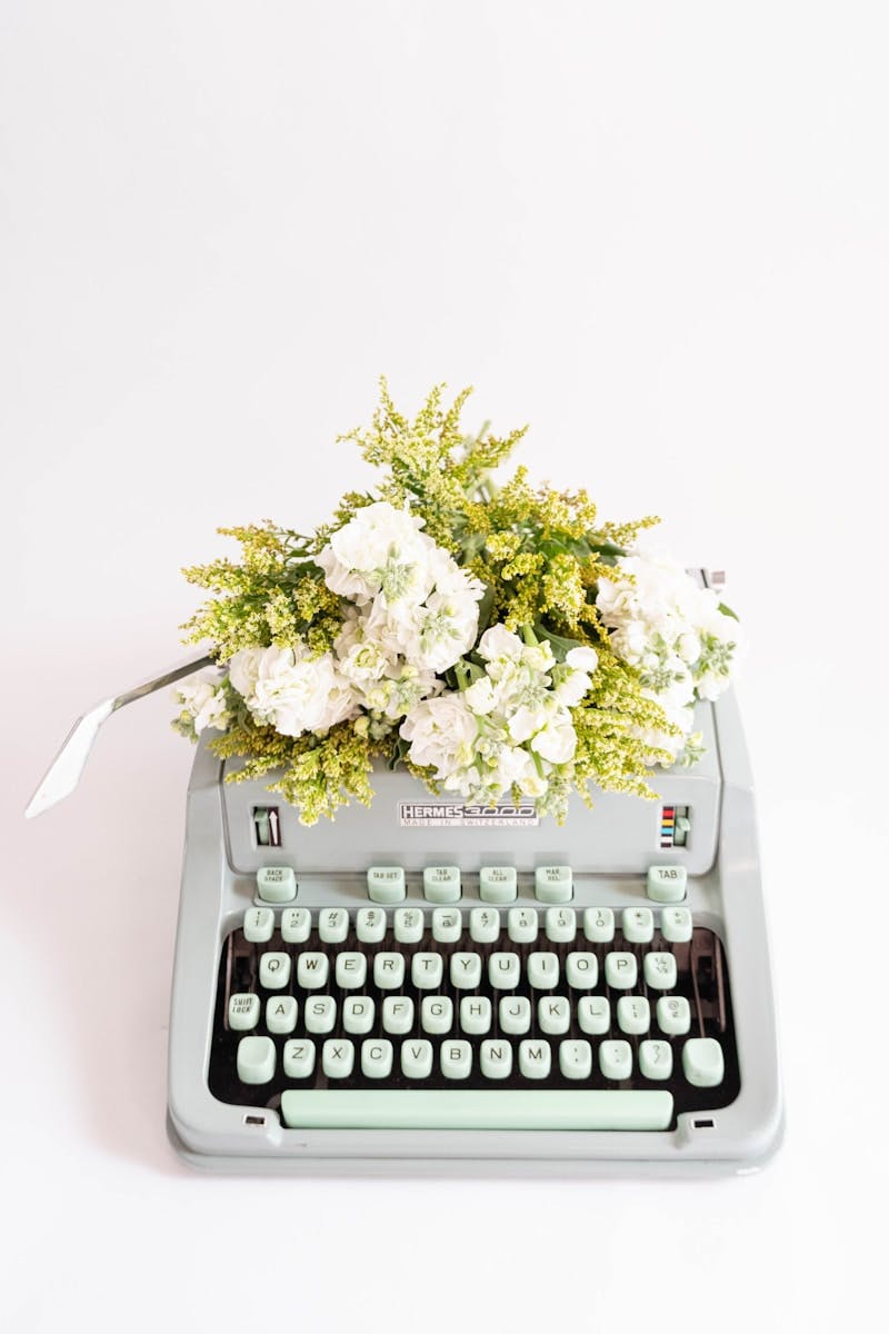 A typewriter with white florals and greenery.