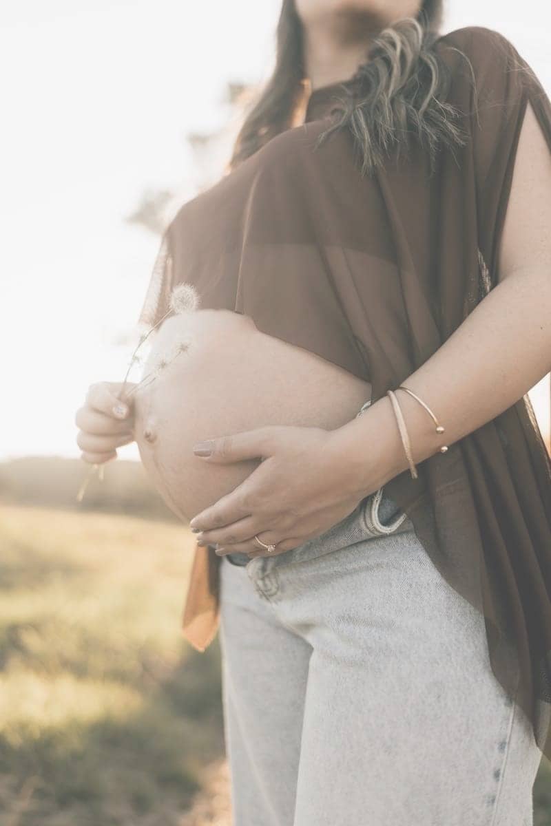 Pregnant woman holding her belly at sunset