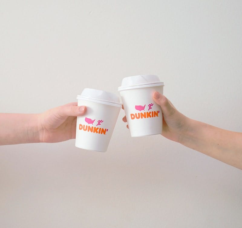 two people with white Dunkin' Donuts paper cups