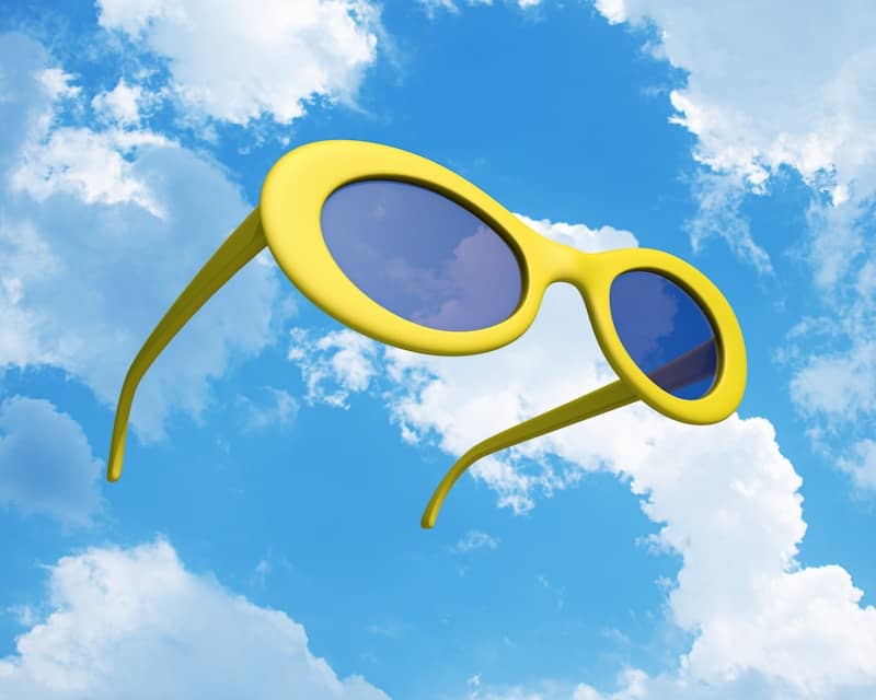 Bright yellow sunglasses floating in a sunny blue sky