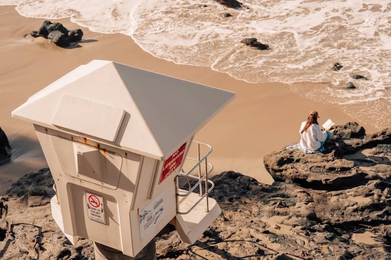 Lifeguard station and a woman reading on the shore.