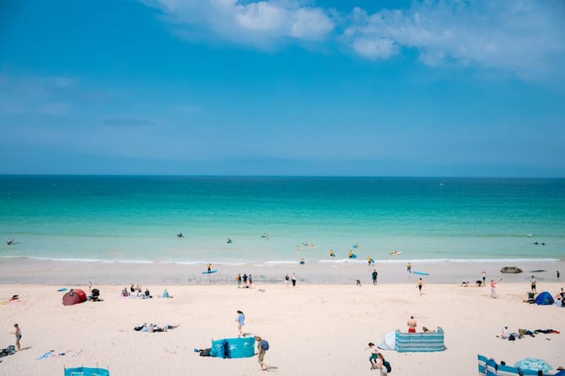 People enjoying a sunny day on a vibrant turquoise beach.