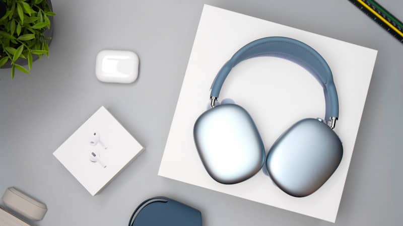 Blue over-ear headphones and white airpods on a white box.