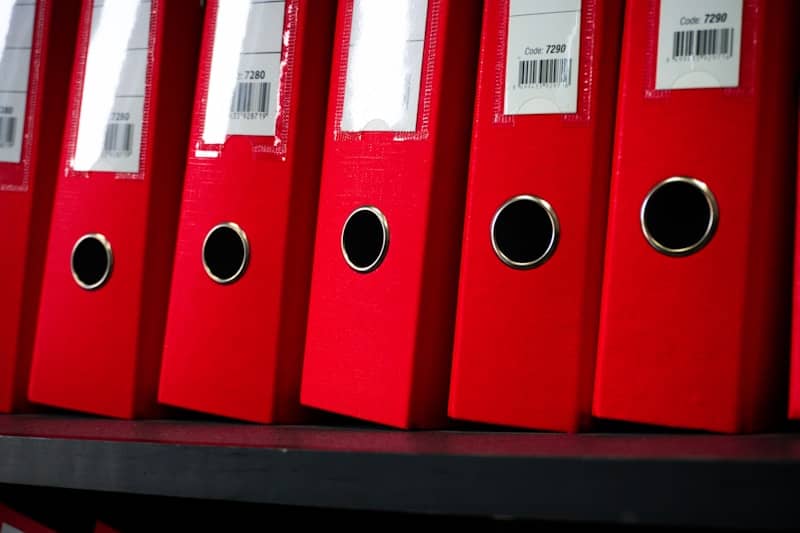 Red file folders are neatly arranged on a shelf