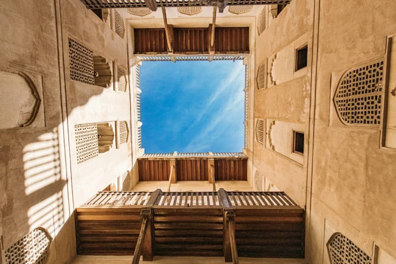A low-angle view of a traditional courtyard with wooden balconies and blue sky