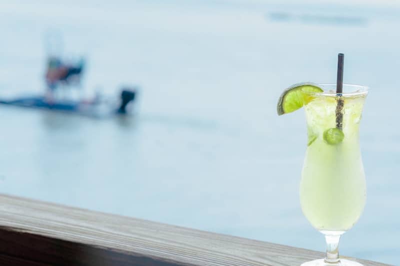 Lime cocktail with a boat in the background.