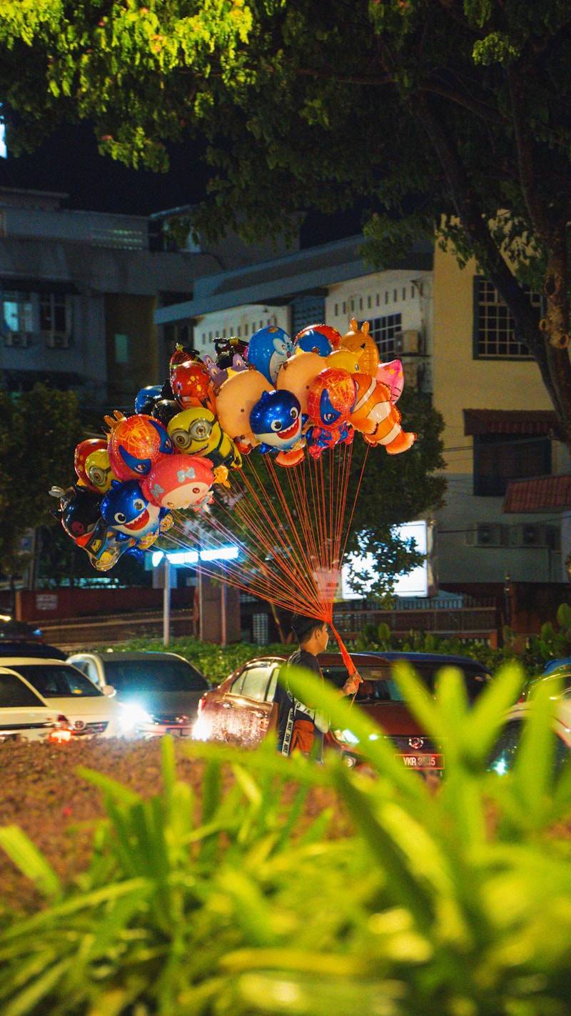 A person holding a bunch of colorful character balloons