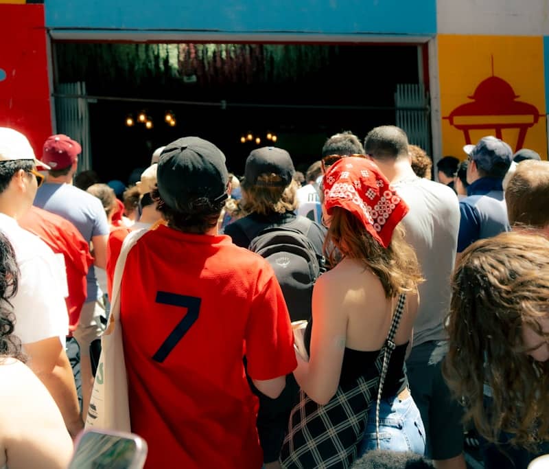 A crowd of people walking towards a colorful building entrance.