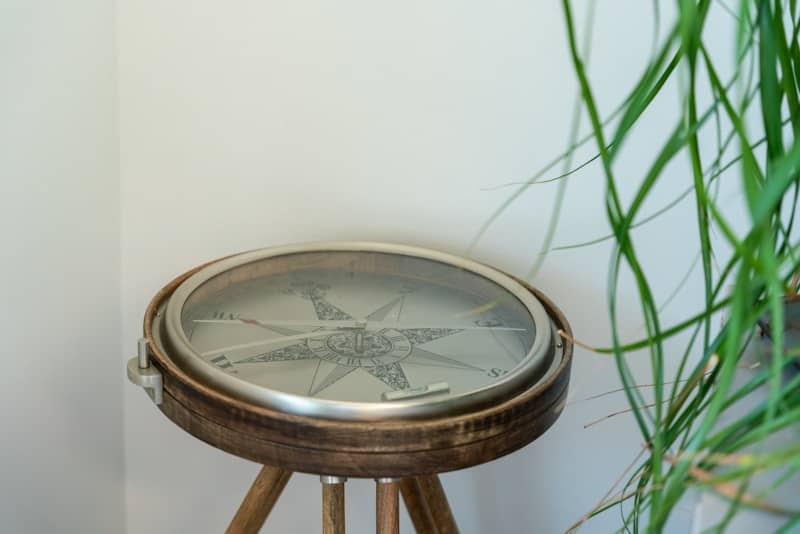A compass sits on a wooden tripod.