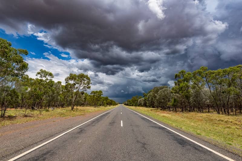 Road leads straight toward a dark, stormy sky.