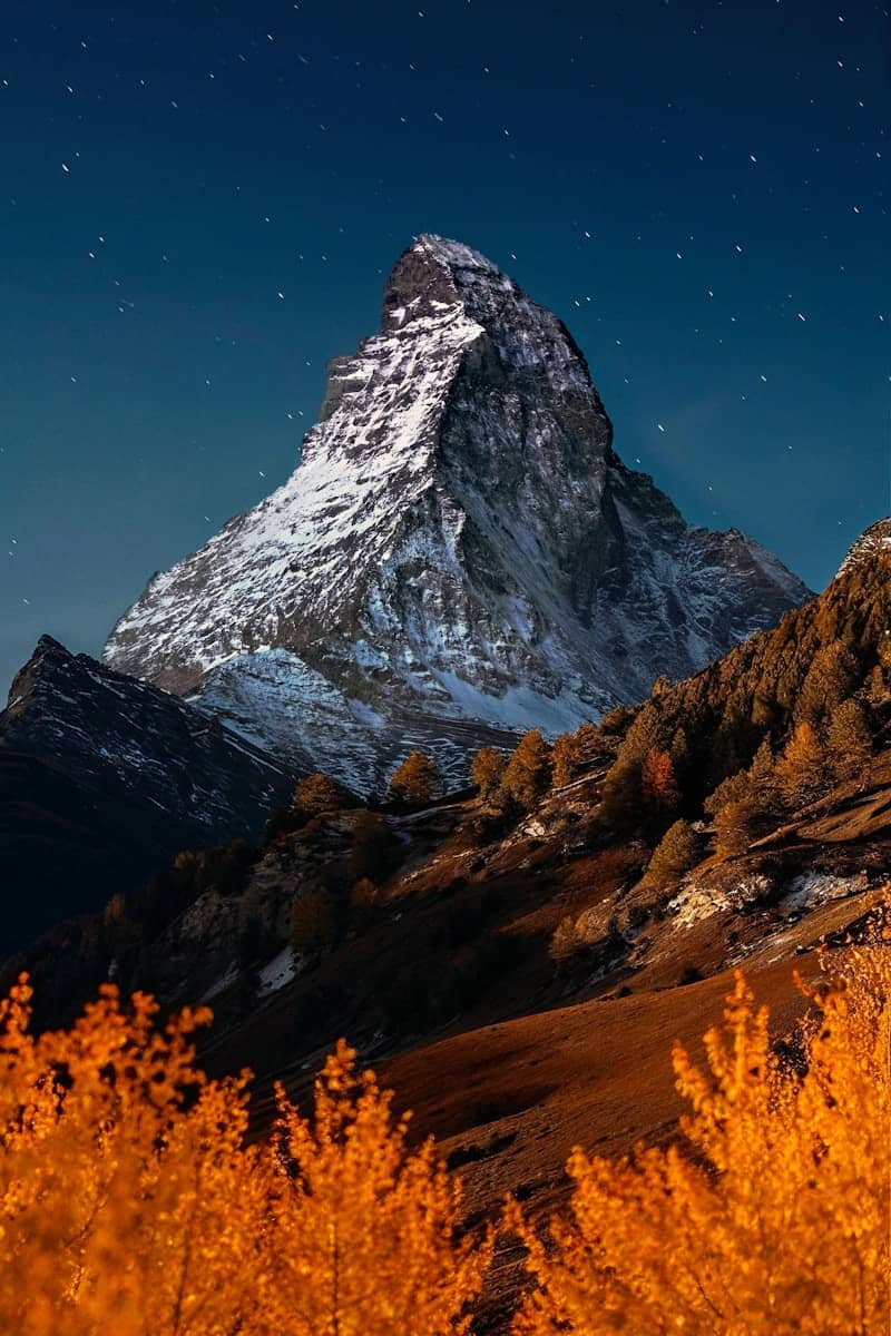 Snow-capped mountain peak under a starry night sky.