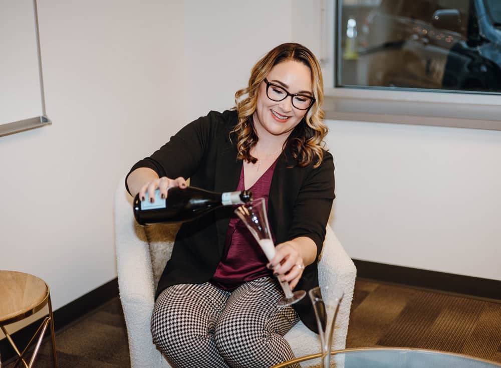 Rachael Woods, Owner of Woods MarCom celebrates with champagne