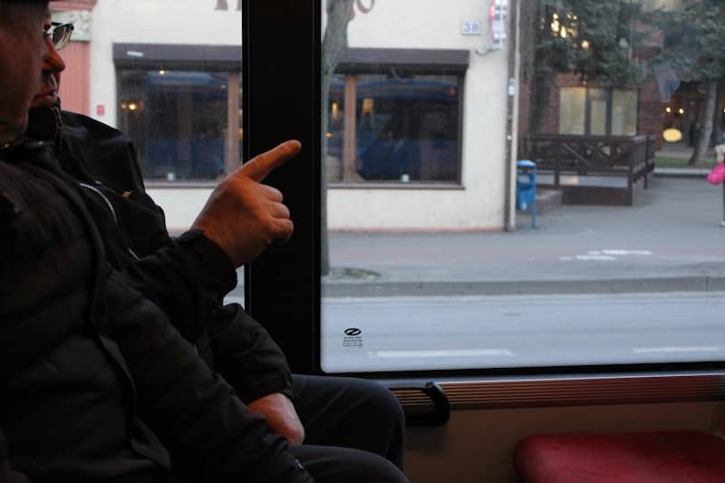 A man sitting on a bus pointing at something