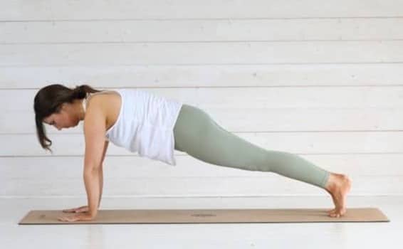 Woman performing a plank exercise on a yoga mat.