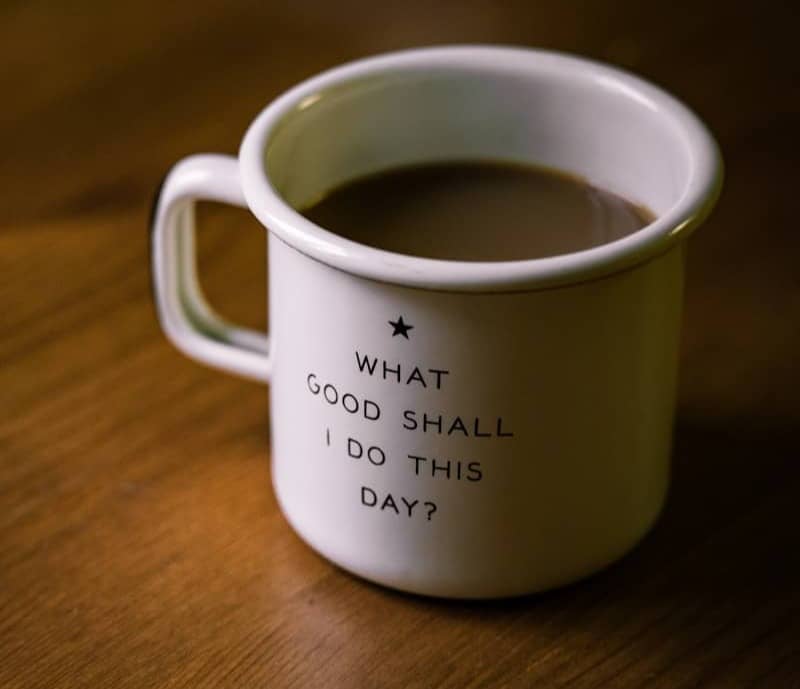 white and black ceramic cup filled with brown liquid on brown wooden sufface