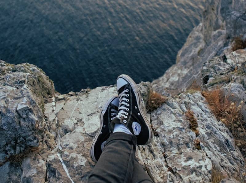 person wearing black-and-white Converse All-Star sneakers