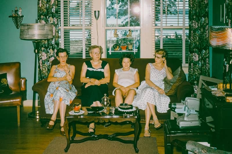 Four women sitting on a couch in a living room.