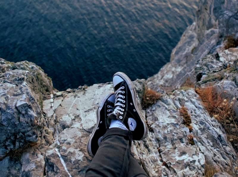 person wearing black-and-white Converse All-Star sneakers