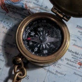 round brass-colored compass on map