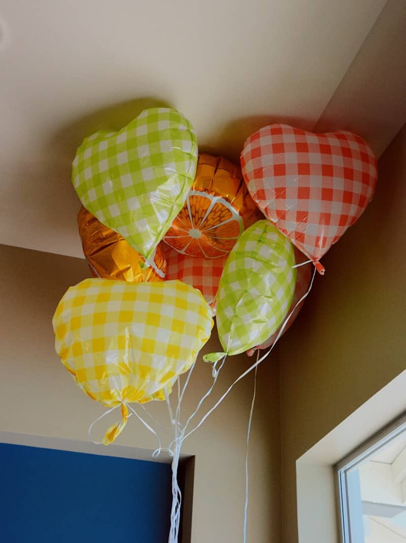 Gingham heart and orange slice balloons near ceiling