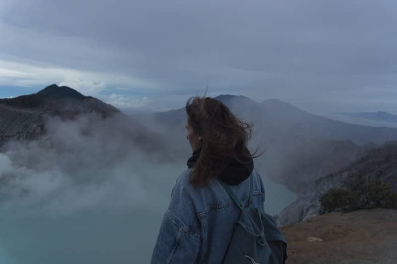 Woman looking at a misty volcanic crater lake