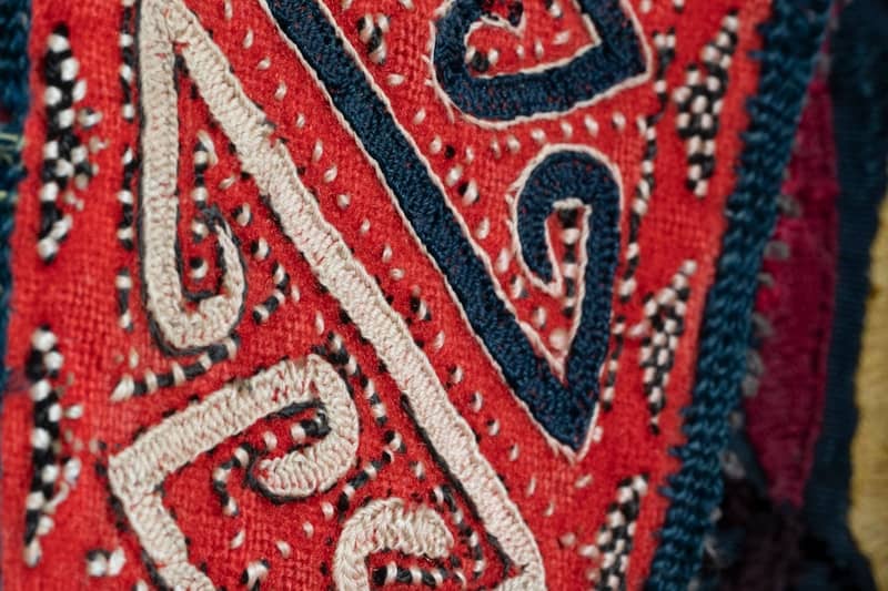 Close-up of intricate red textile with white and blue patterns.