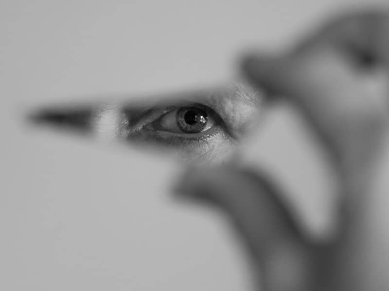 Eye peers through a tiny space in a hand.