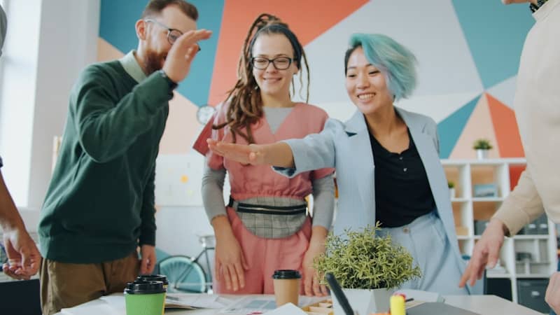 A group of people in a colorful office giving a high five