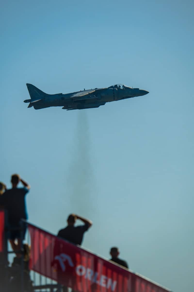 Jet airplane flying with smoke trail over spectators