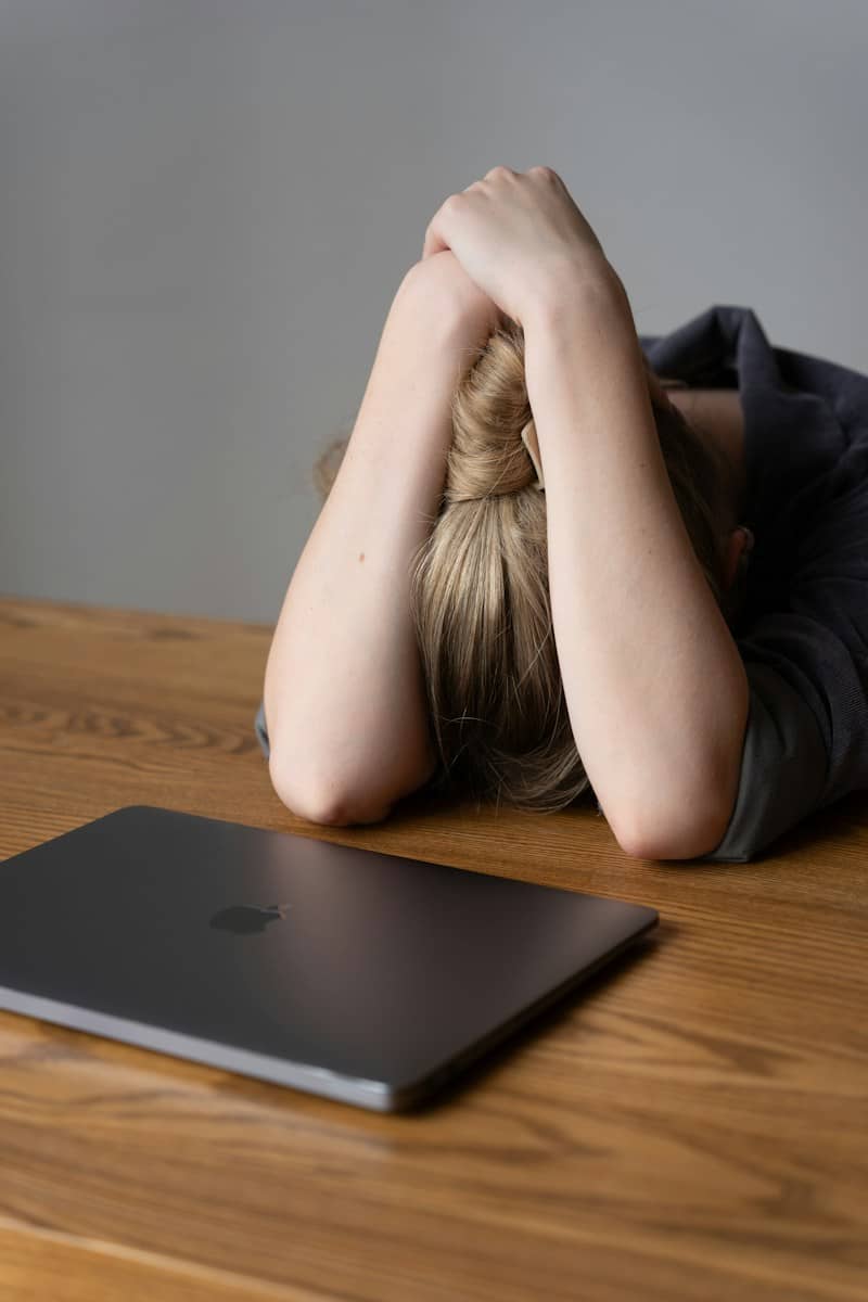 A person with head in hands next to a laptop