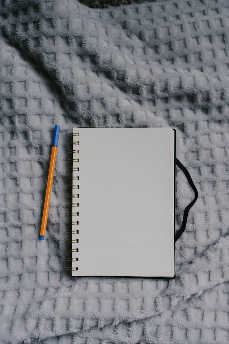 Notebook and pen rest on a cozy blanket.