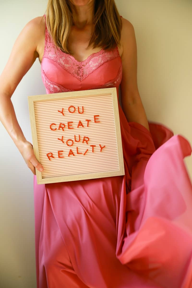 Woman holds a sign that says, "you create your reality."