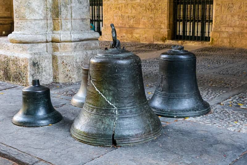 Old bronze bells sit on the stone floor.