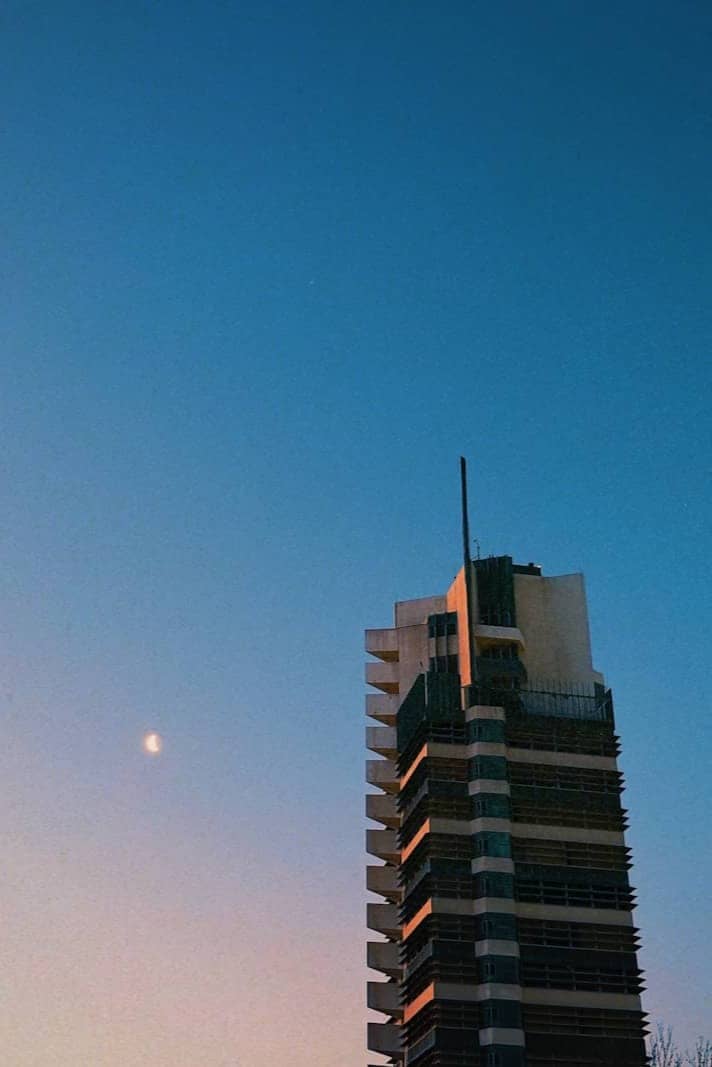 Modern skyscraper against a twilight sky with crescent moon