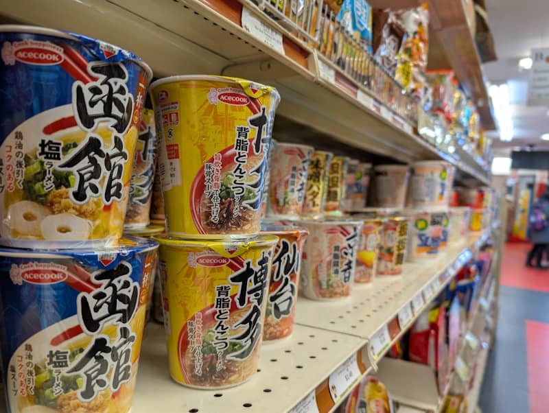 Shelves stocked with various instant noodle cups.
