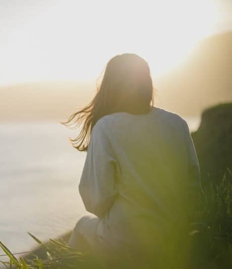 woman wearing gray long-sleeved shirt facing the sea