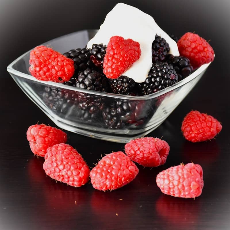 Bowl of blackberries and raspberries with cream