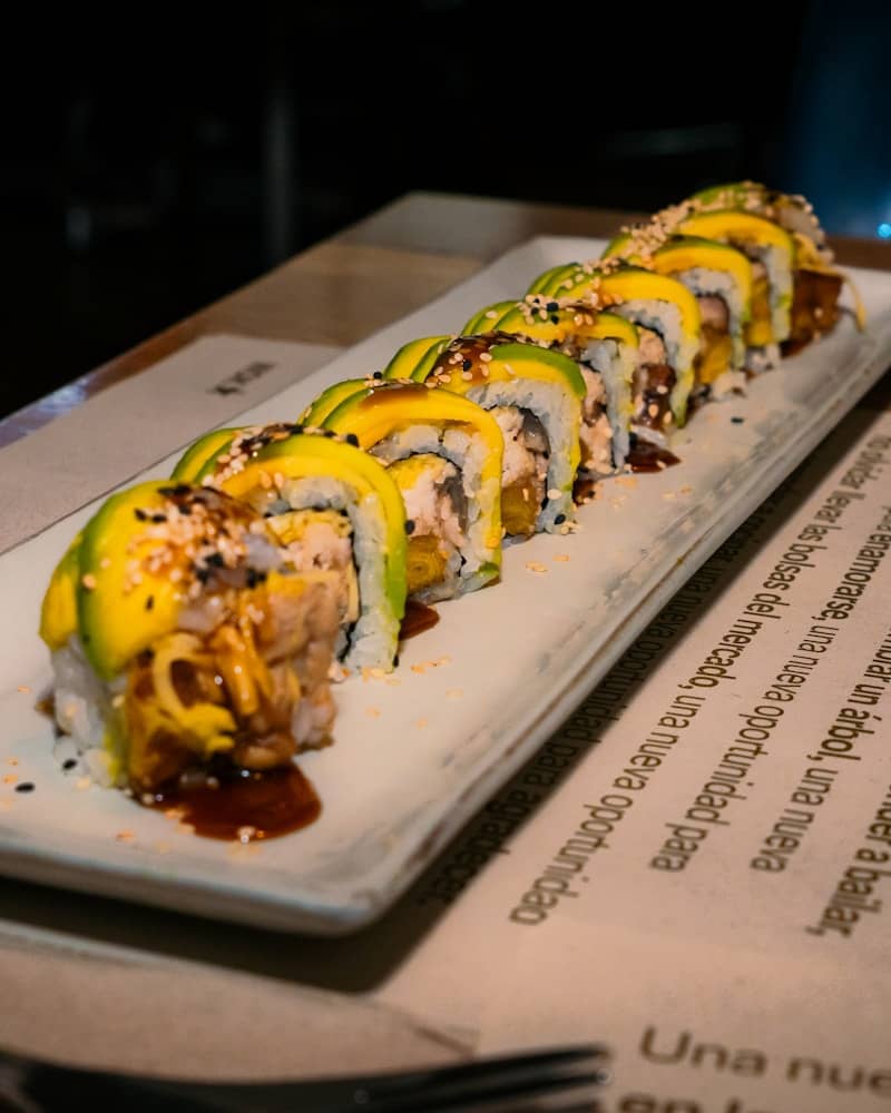 Delicious sushi rolls with avocado on a long plate.