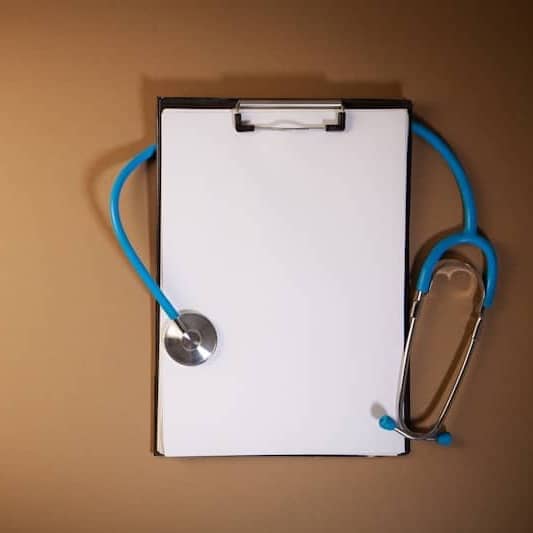 Clipboard with stethoscope on a brown background