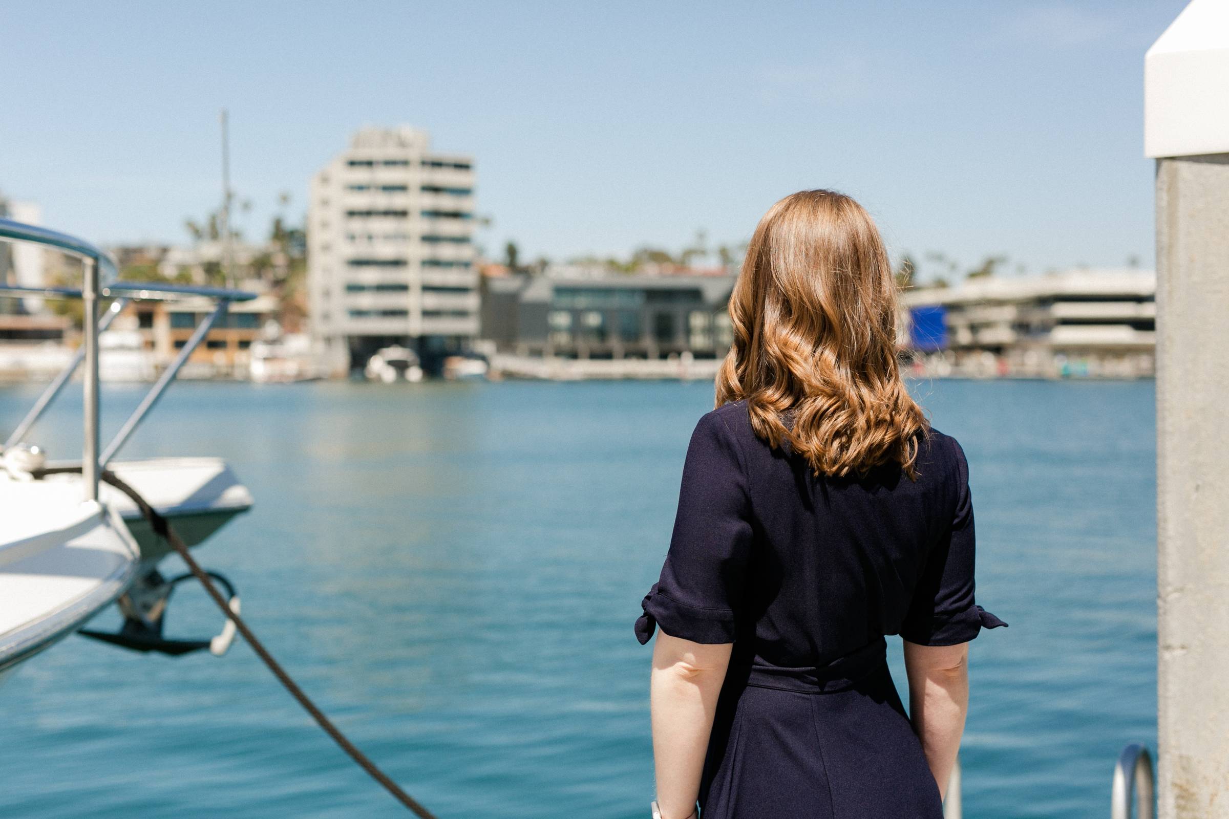Woman looks out on blue ocean water in the harbor