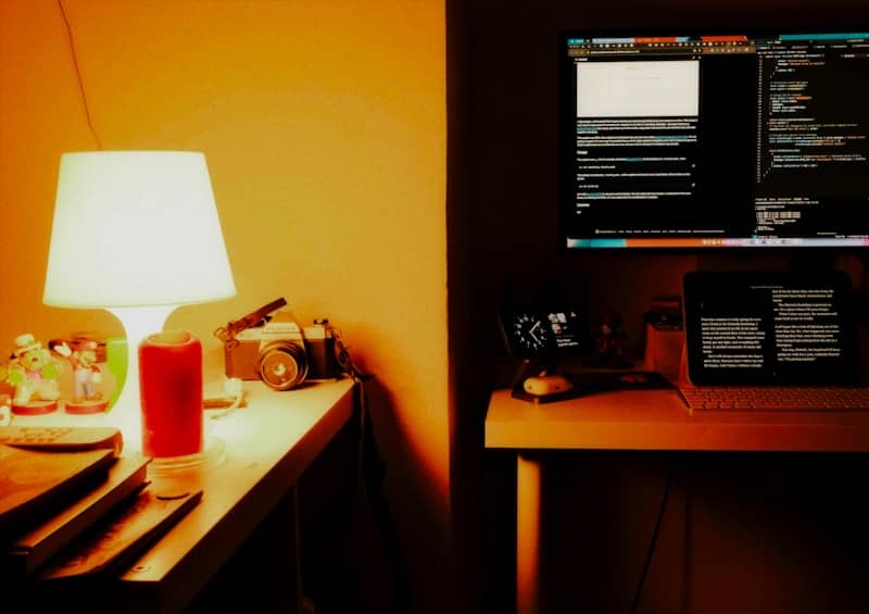 Desk with computer, lamp, and vintage camera.