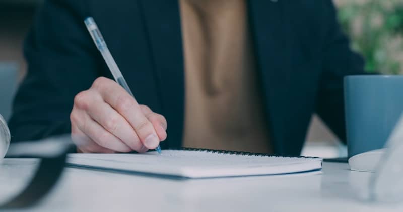 A person sitting at a table with a pen in their hand