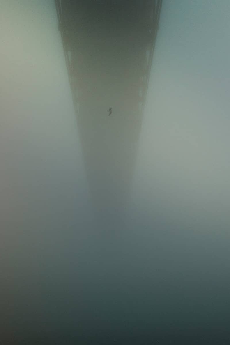 A bridge extends into heavy fog.