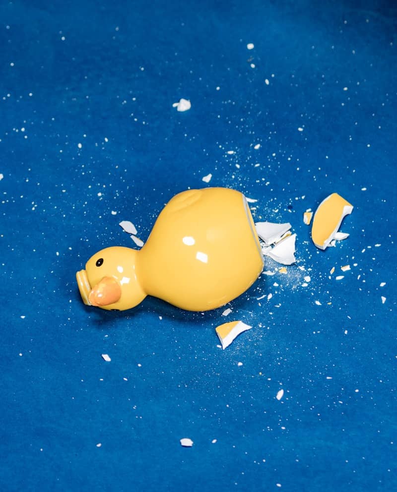 A broken yellow rubber duck on a blue surface