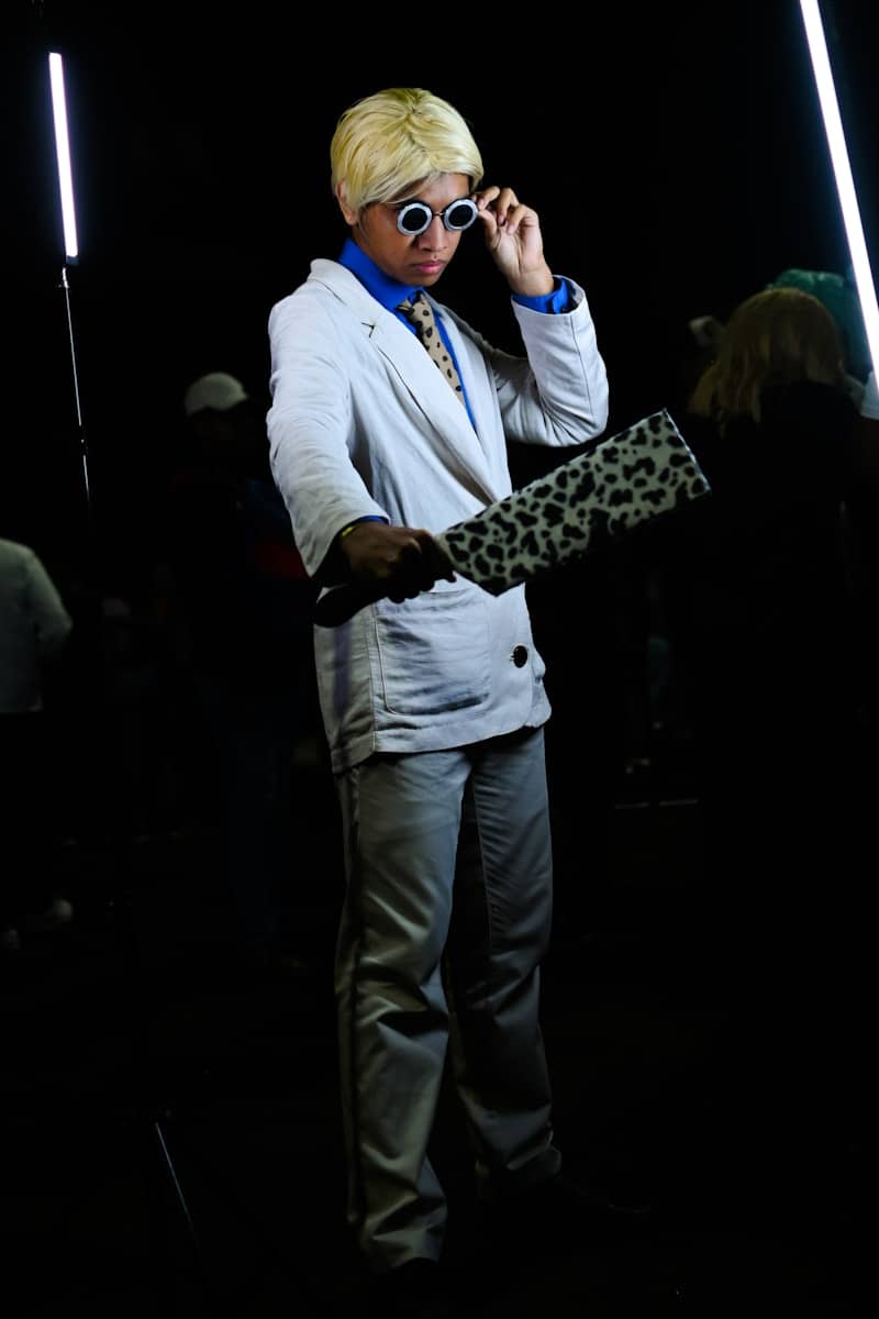 A man in a white suit and sunglasses talking on a cell phone